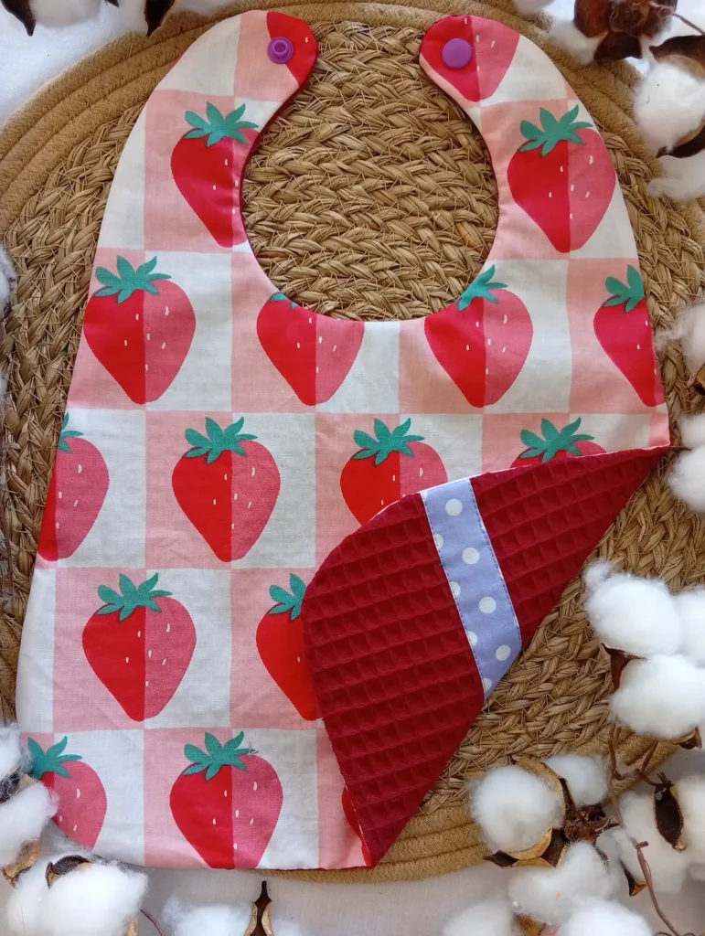 bavoir réversible imperméable et absorbant en coton enduit et éponge nid d'abeille. Motif fraises et pois