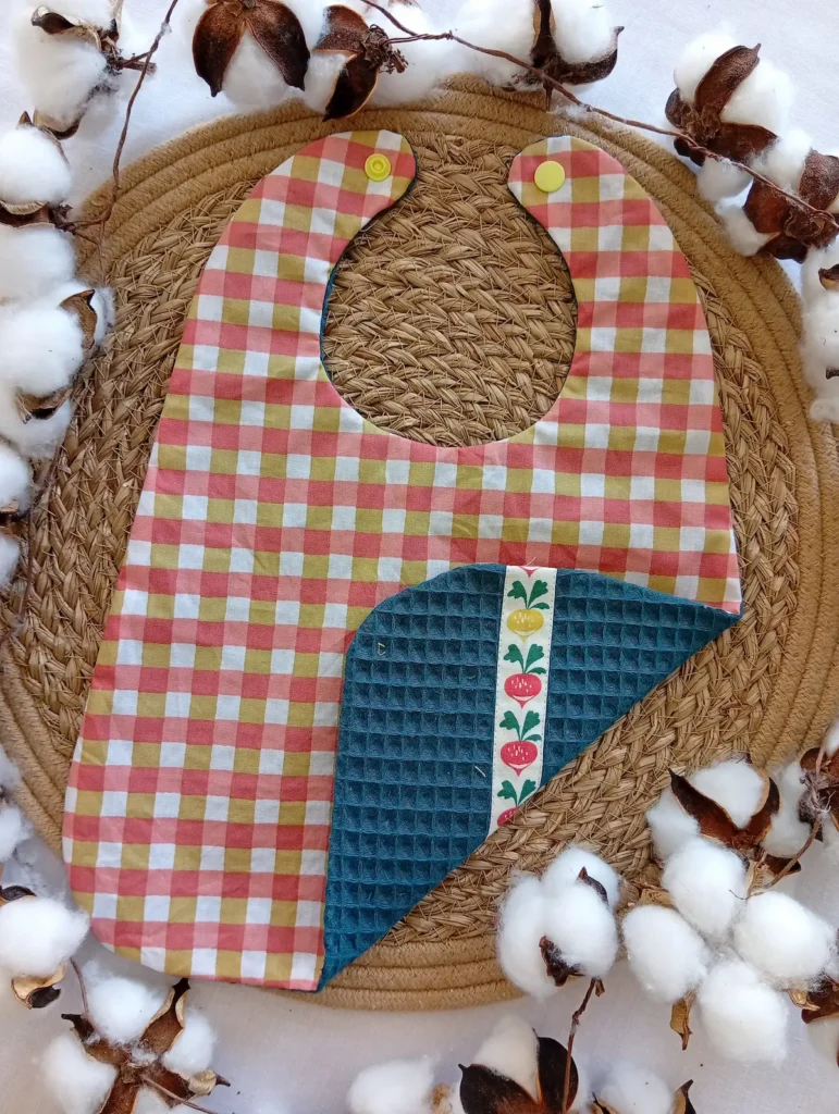 Bavoir réversible imperméable et absorbant en coton enduit et éponge nid d'abeille avec motif vichy et radis.
