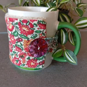 housse de tasse avec petites fleurs rouges avec feuilles vertes sur fond blanc et bouton tranparent fuschia, doublure en bambou taupe