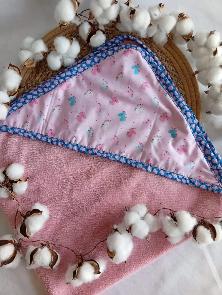 Sortie de bain bébé en éponge bambou rose avec capuche motif licorne et biais fleuri, Cous Mel fait main en Normandie, France