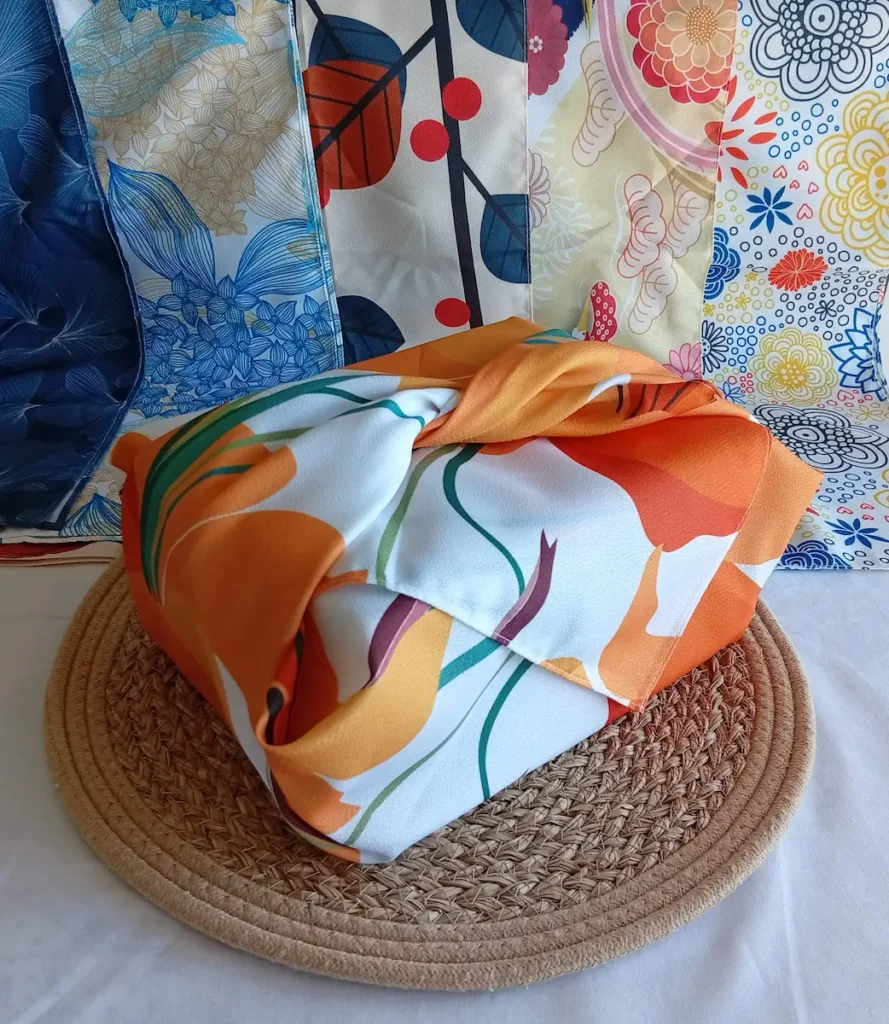 Furoshiki emballage cadeau japonais motif Lys, embllé autour d'une boîte. En fond : 5 motifs différents de furoshiki